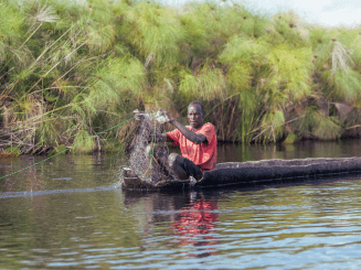 A man fishes aboard a canoe near Old Fangak, located alone one of the world's largest wetlands, the Sudd region.