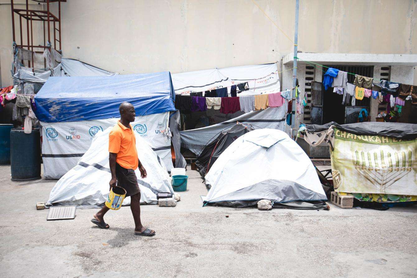 A man walks past tents for displaced people in Haiti.