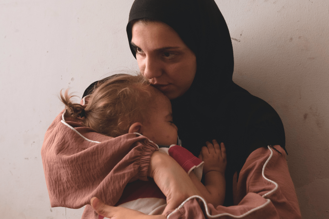 Zeinab Ozeir calms the cries of her child in the Azarieh shelter in central Beirut, where she lives in a room with her husband and their four children.