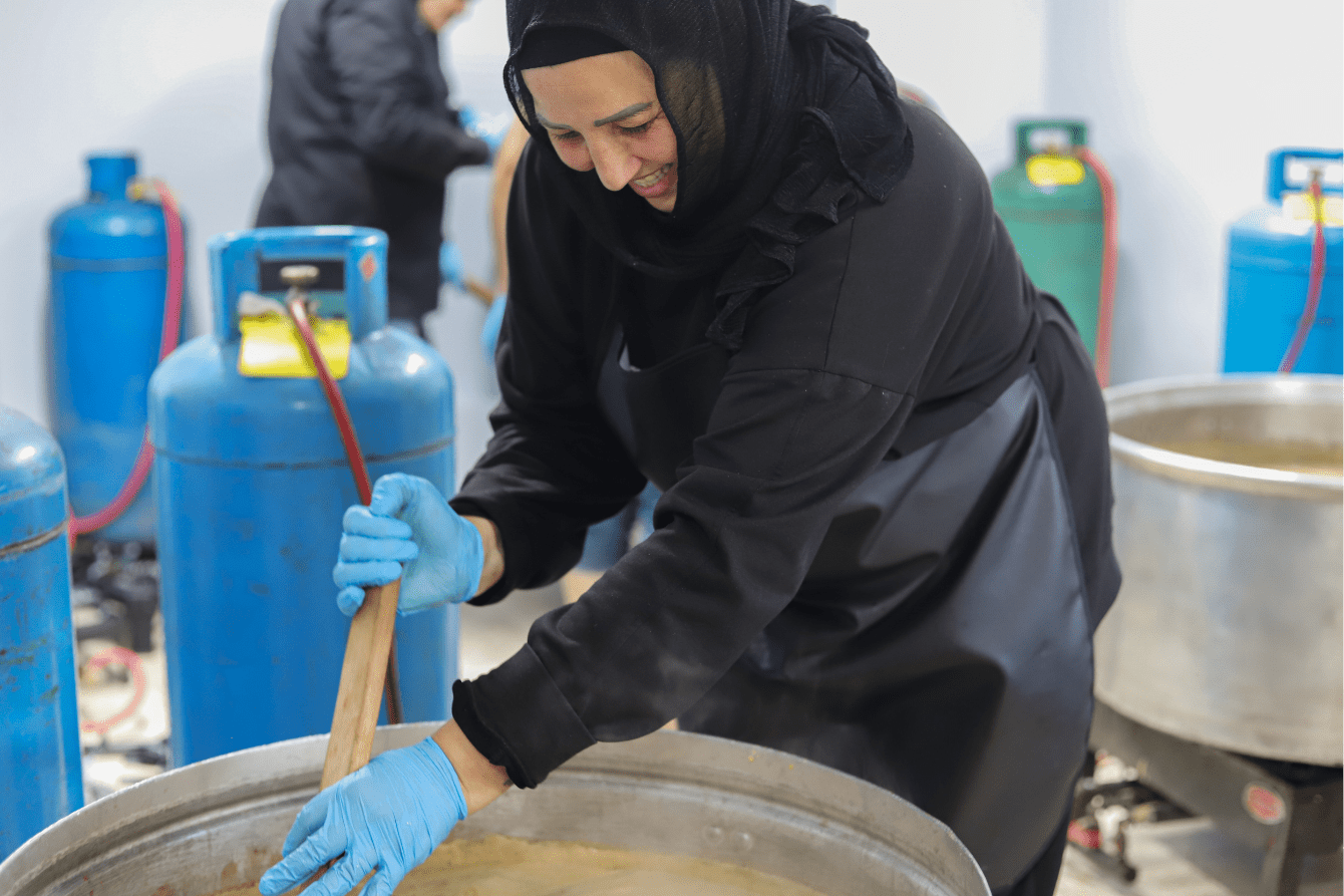 A woman smiles as she cooks in Azarieh shelter, Lebanon.