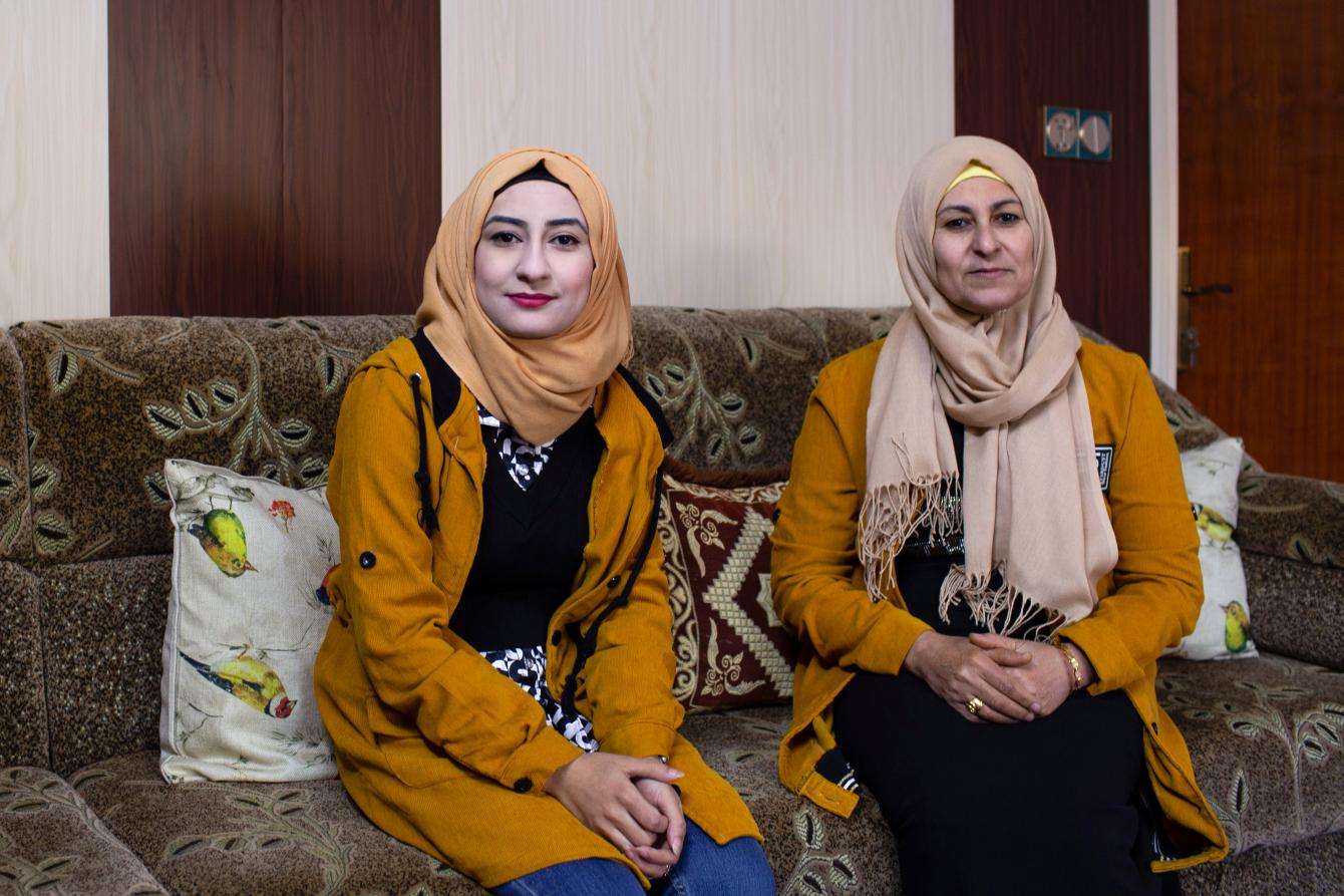 Two women sitting on a couch, smiling