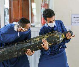 Workers carry an oxygen cylinder to the intensive care unit.